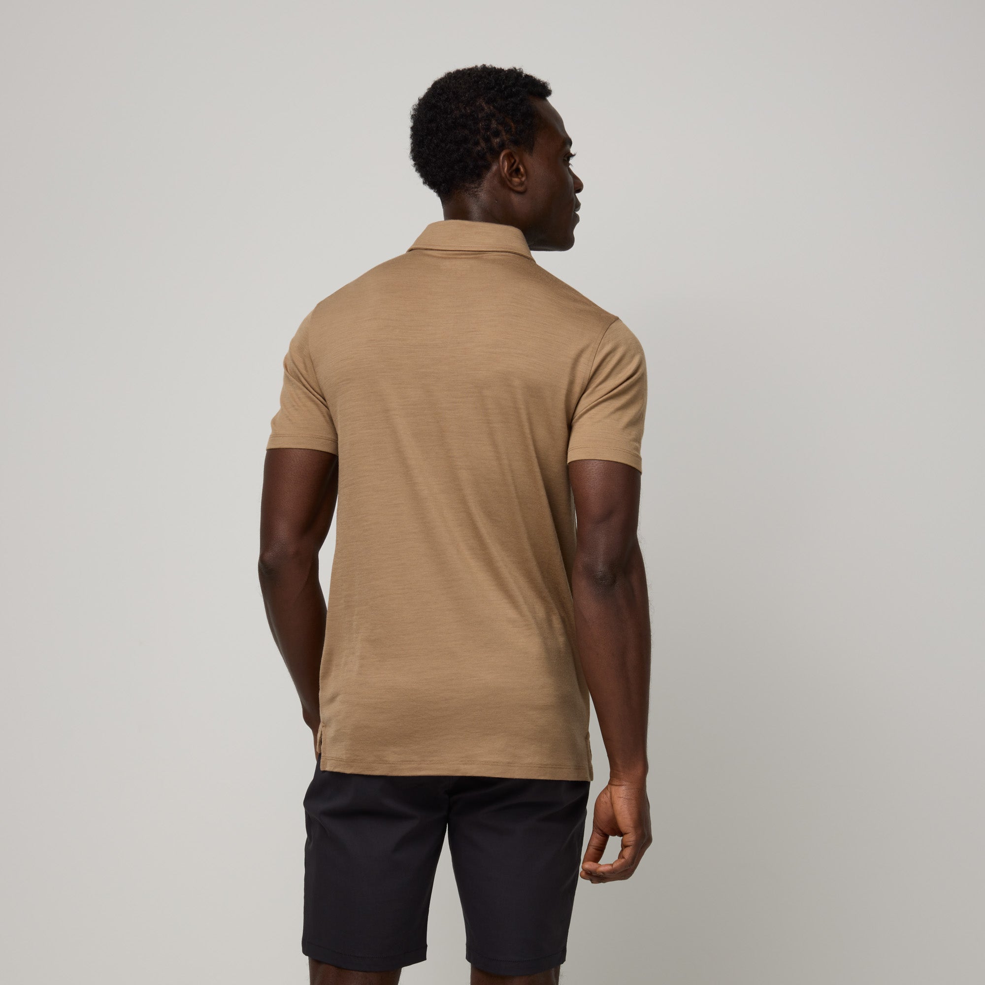 Model wearing 100% Merino Wool Polo Shirt in Cedarwood, a warm soft brown color. This short sleeve, crew neck t-shirt is available in sizes XS-XXL.