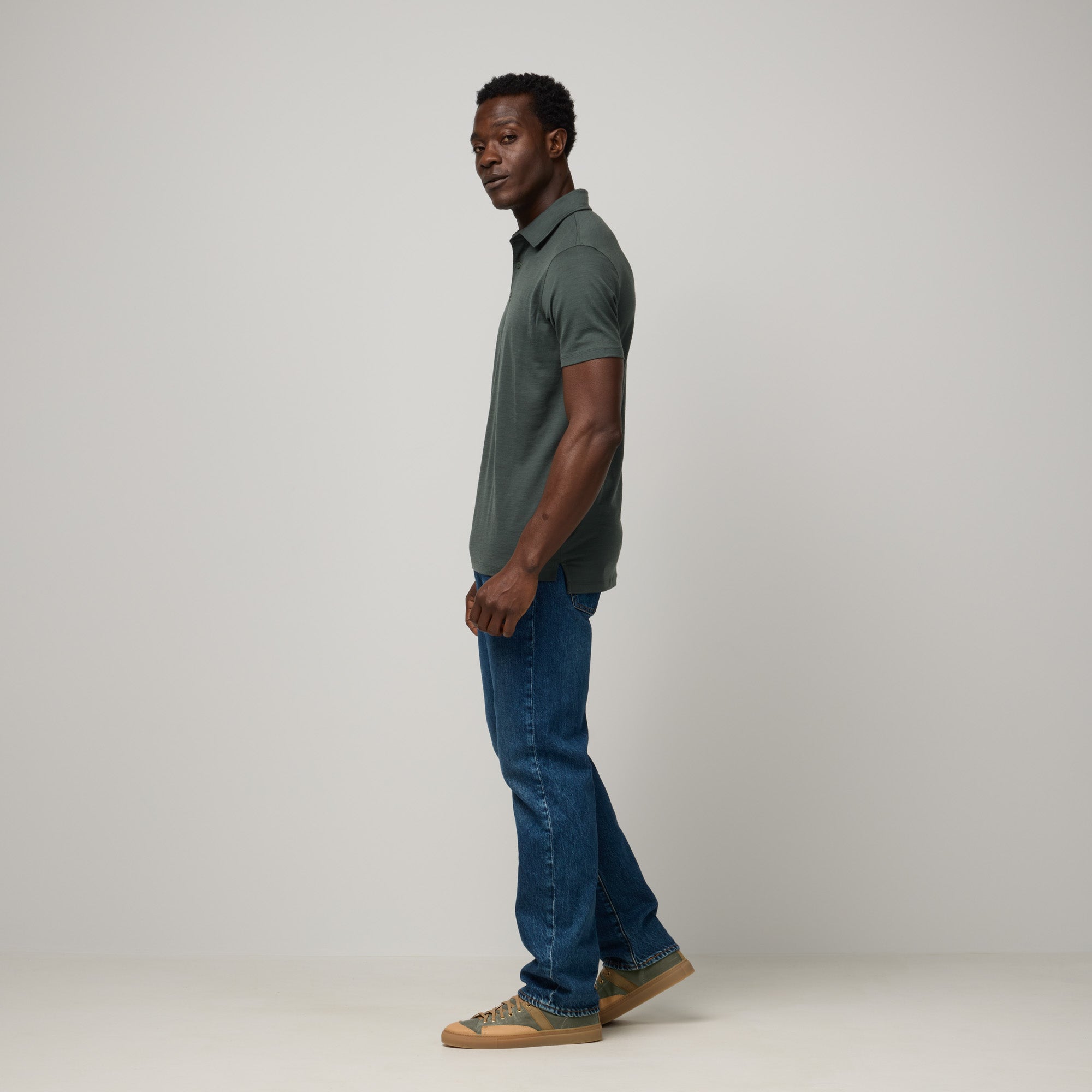 Model wearing 100% Merino Wool Polo Shirt in Hunter Green, a dark green with blue undertones. This short sleeve, crew neck t-shirt is available in sizes XS-XXL.