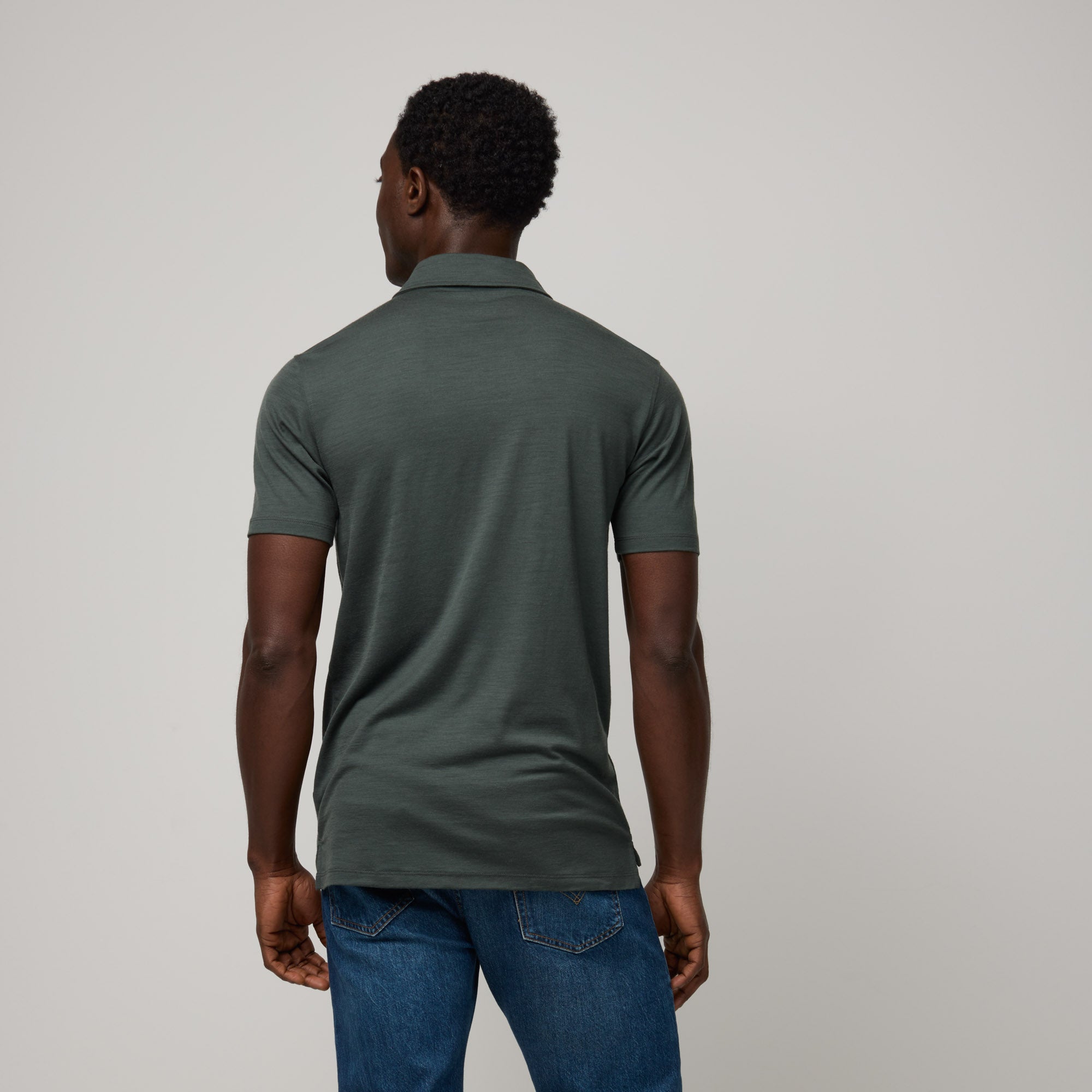Model wearing 100% Merino Wool Polo Shirt in Hunter Green, a dark green with blue undertones. This short sleeve, crew neck t-shirt is available in sizes XS-XXL.