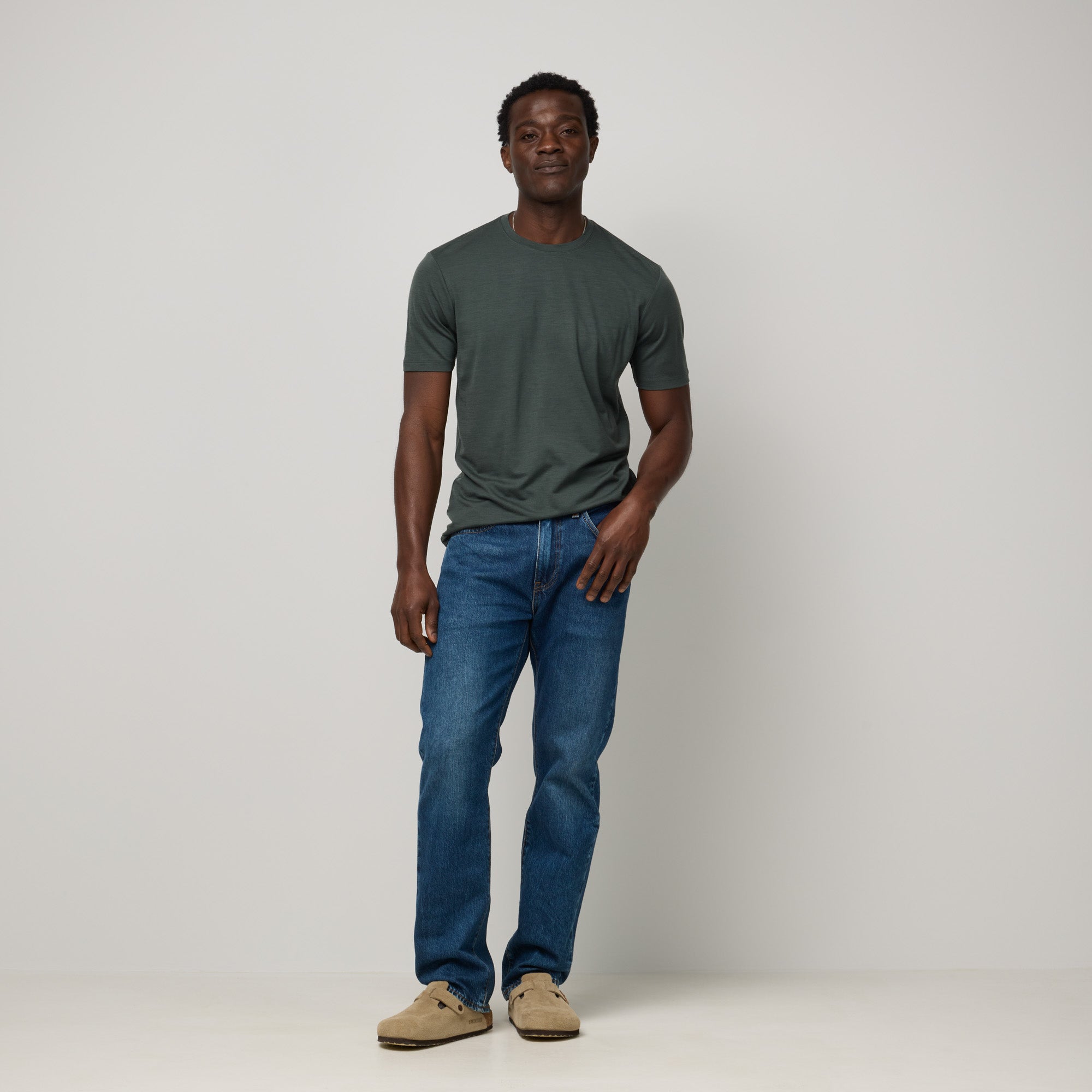 Model wearing 100% Merino Wool T-Shirt in Hunter Green, a dark green with blue undertones. This short sleeve, crew neck t-shirt is available in sizes XS-XXL.