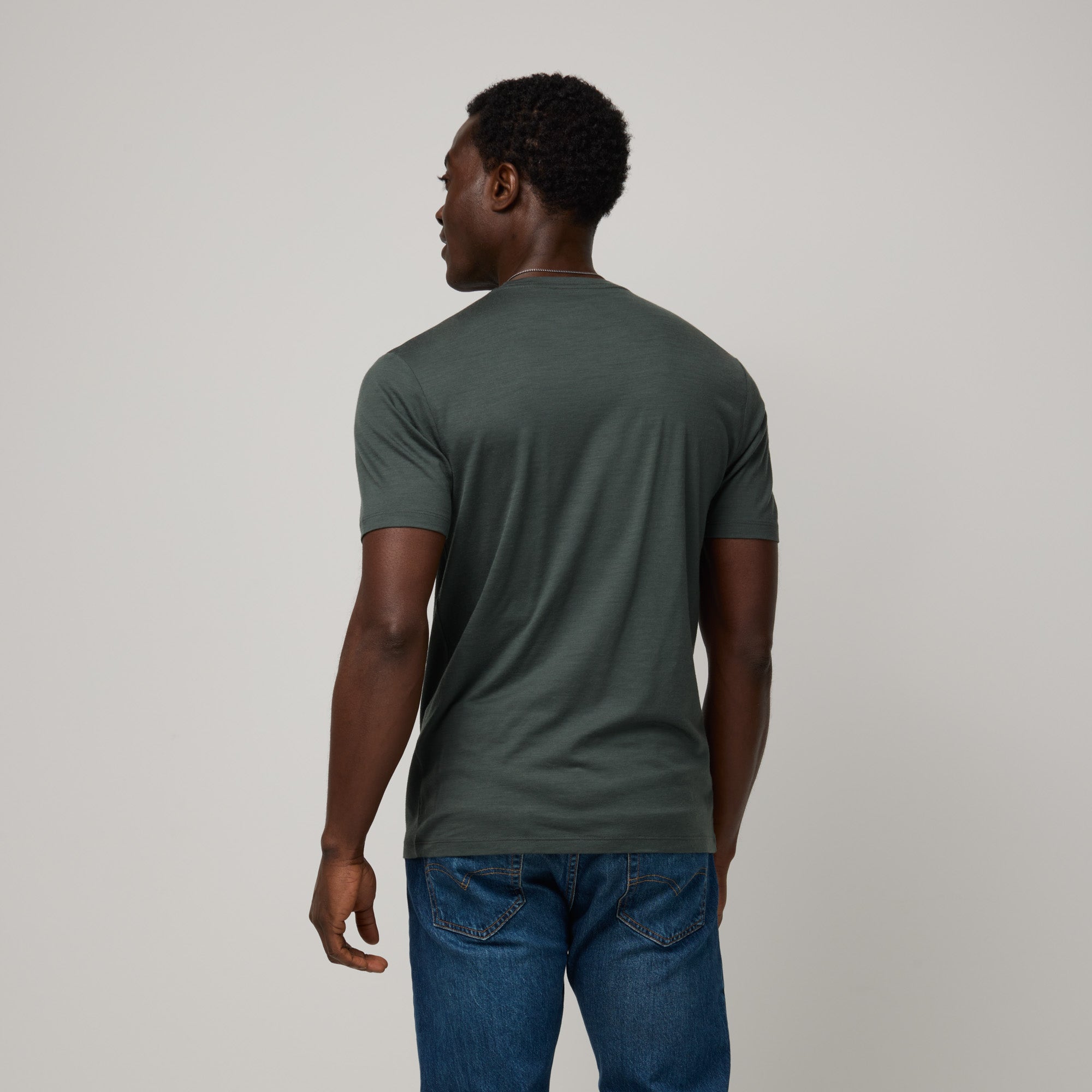 Model wearing 100% Merino Wool T-Shirt in Hunter Green, a dark green with blue undertones. This short sleeve, crew neck t-shirt is available in sizes XS-XXL.