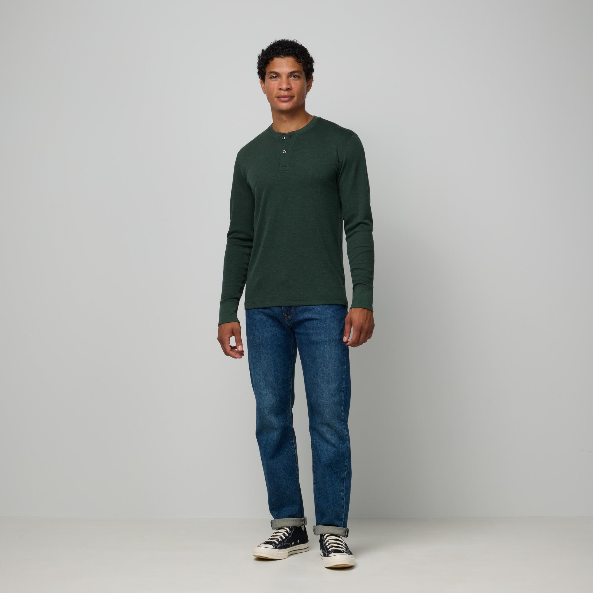 Model wearing merino wool Waffle Henley in Hunter Green, a dark green with blue undertones. This is a long sleeve, crew neck henley shirt available in sizes XS-XXL.