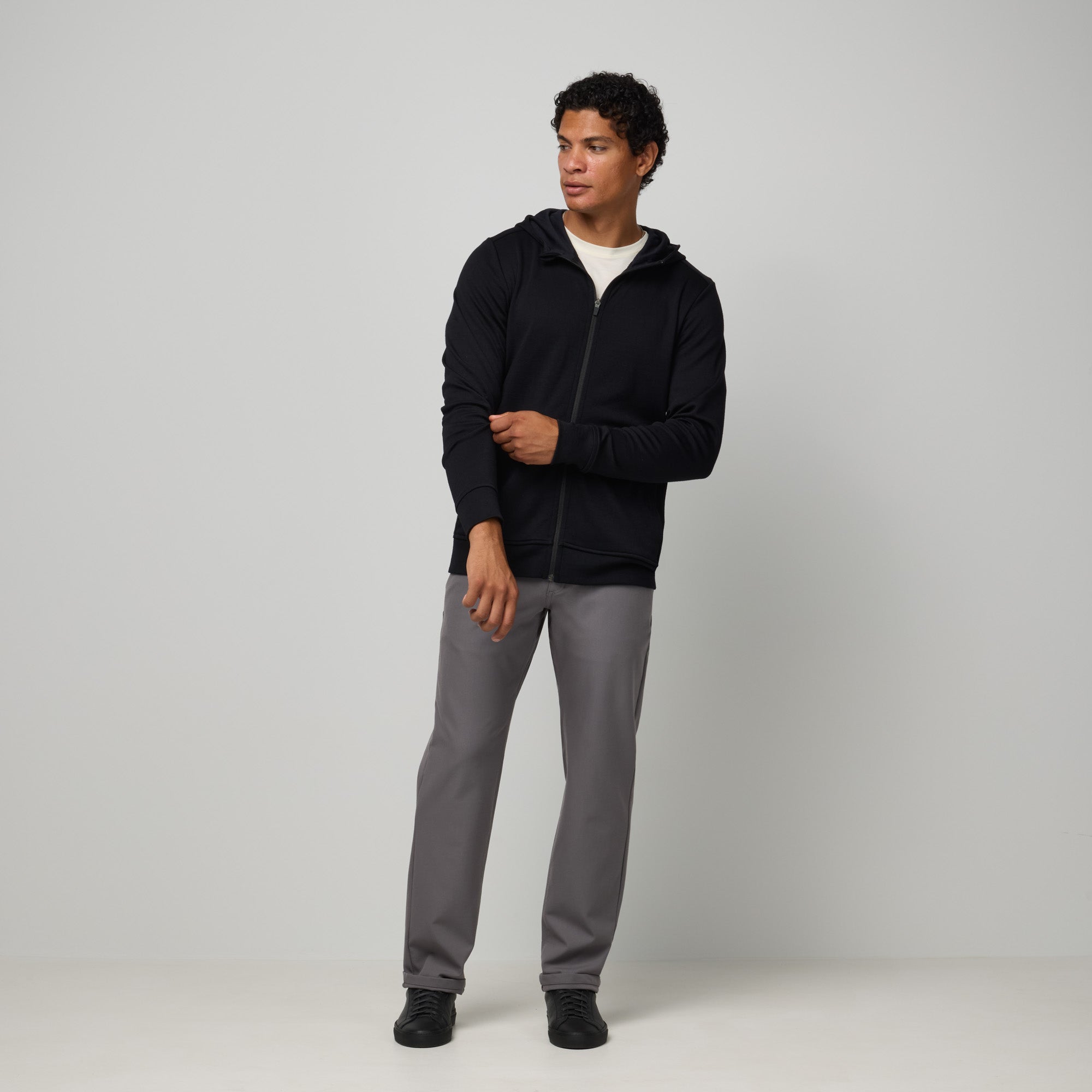 Model wearing merino wool Interlock Travel Hoodie in Black. This is a midweight full-zip hoodie available in sizes XS-XXL.