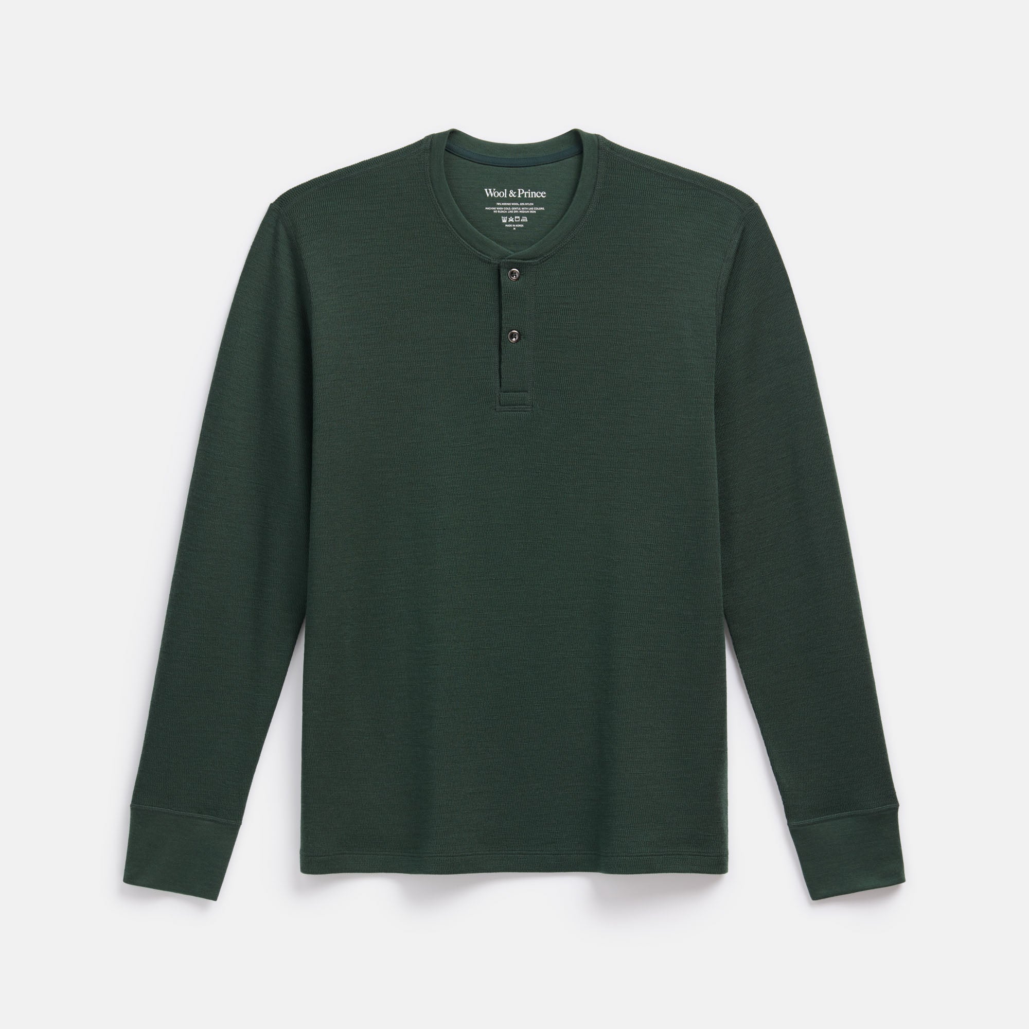 Laydown of merino wool Waffle Henley in Hunter Green, a dark green with blue undertones. This is a long sleeve, crew neck henley shirt available in sizes XS-XXL.