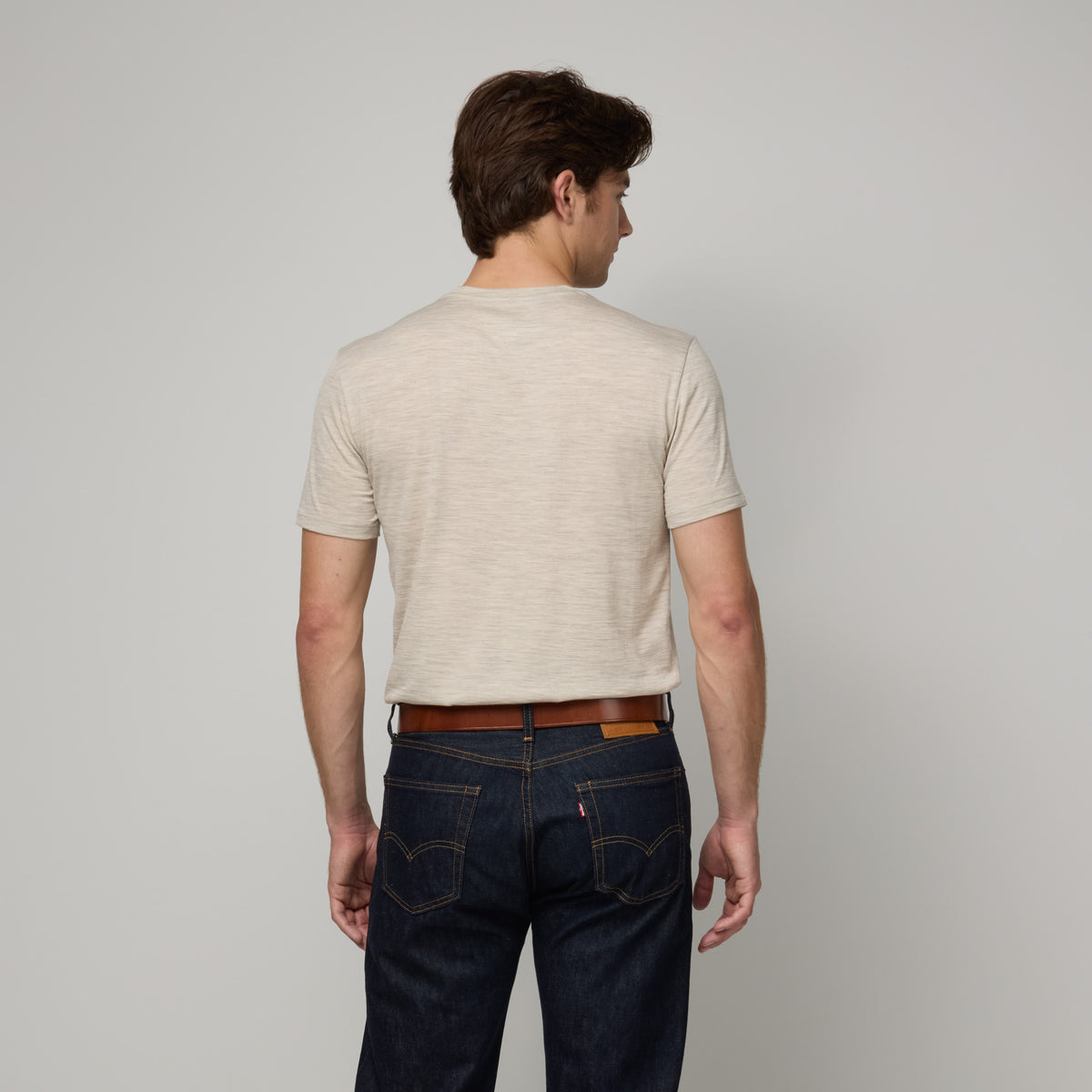 Model wearing merino wool Signature Crew Neck Tee in Oatmeal Heather, a heathered cream color. This is a short sleeve, crew neck tee available in sizes XS-2X