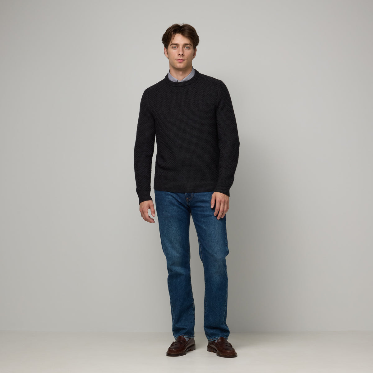 Model wearing 100% merino wool Textured Crew Neck Sweater in Black Heather, a dark gray color. This is a knit available in sizes S-XXL.